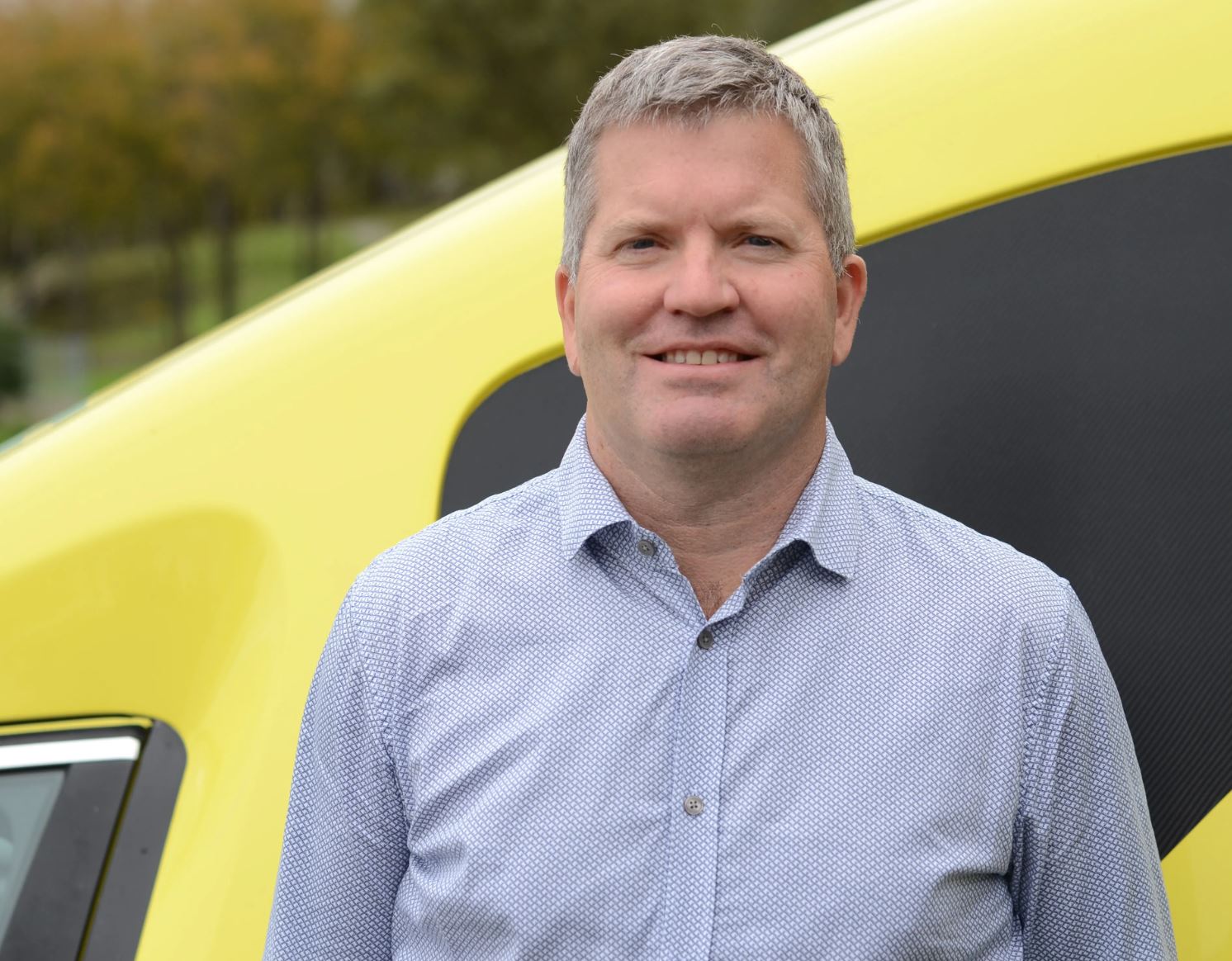 A man standing in front of a yellow car