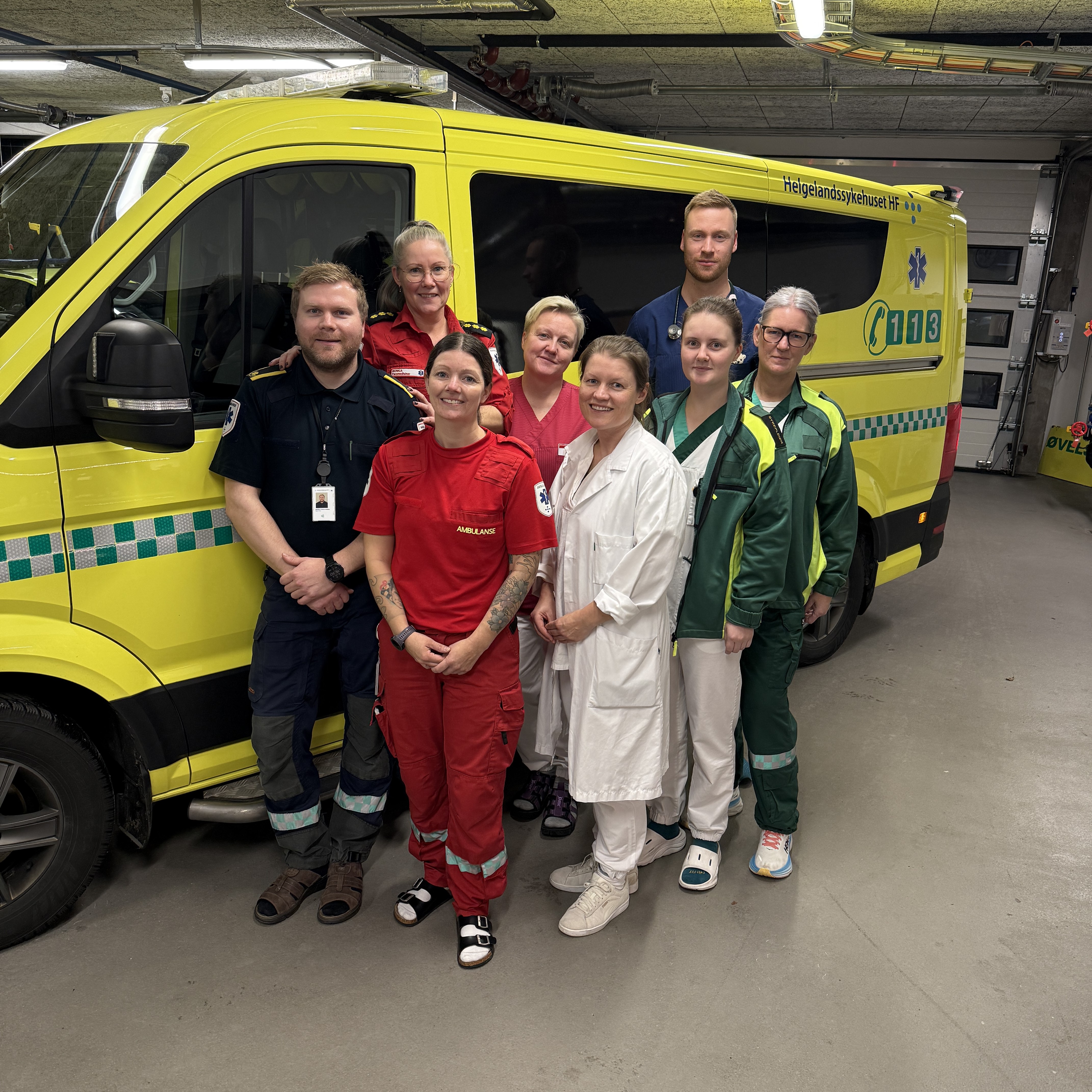 En gruppe mennesker som poserer for et bilde foran en ambulanse